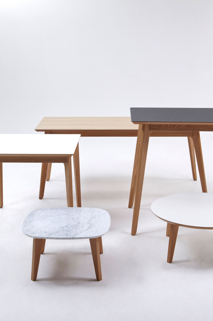 A naughtone Dalby Conference Table with a wood top in the background of an arrangement of other tables in the Dalby family.