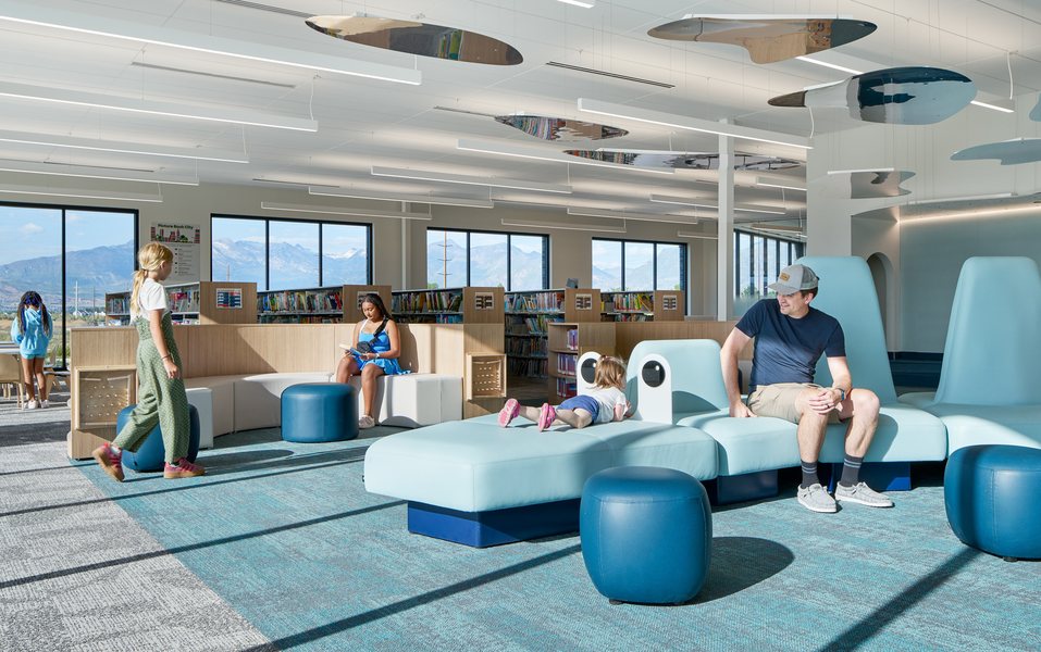 A bright community space with blue lounge seating and soft poufs