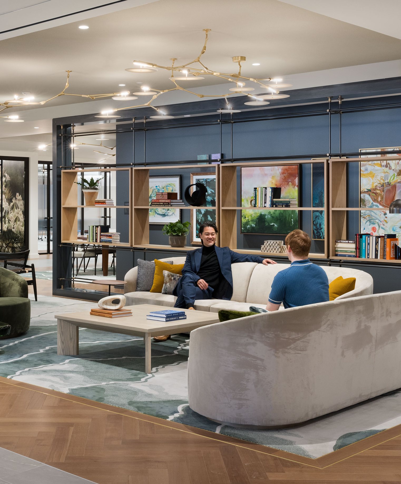 A lounge with curved sofas in front of a navy display wall