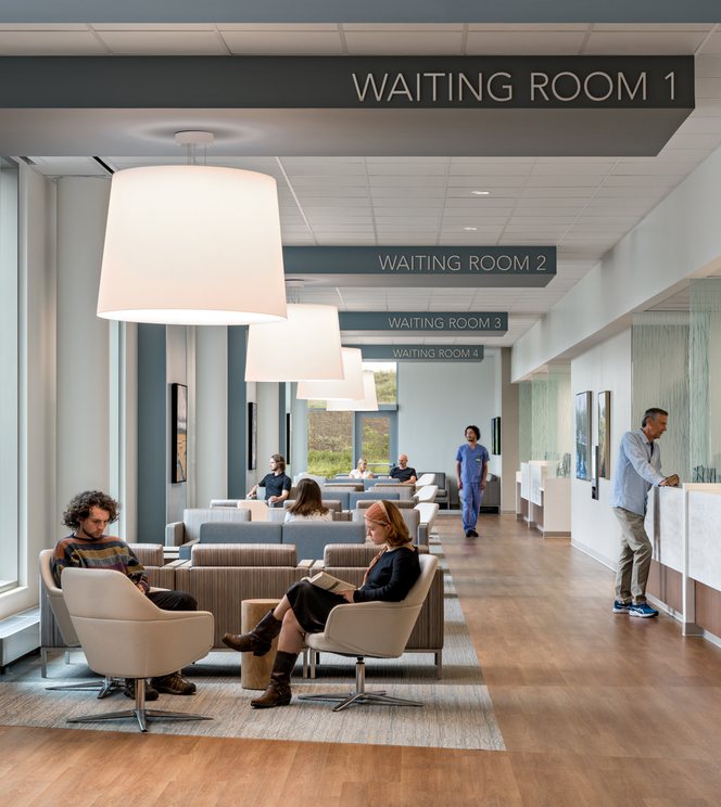 A daylit waiting area with lounge chairs and pendant lighting