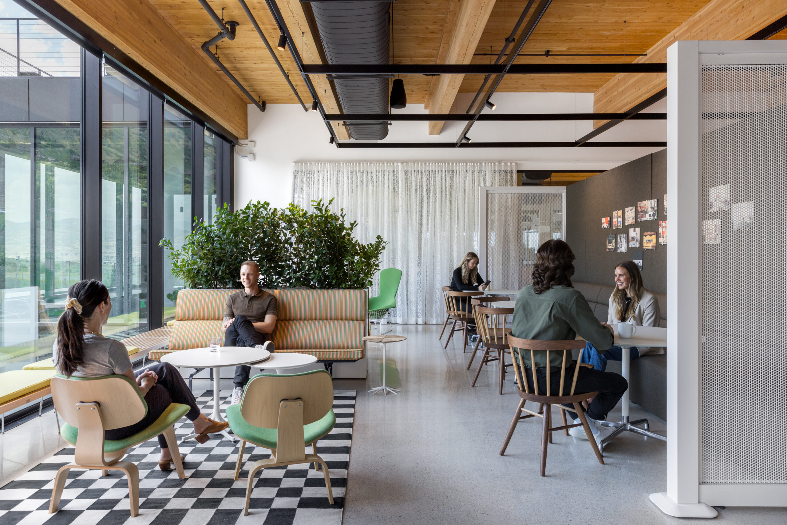 An open lounge and cafe area in a COR showroom, with banquette seating, cafe tables and planting